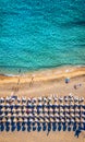 Aerial view of sandy beach with colorful umbrellas, swimming people in sea bay with transparent blue water at sunset in summer. Royalty Free Stock Photo