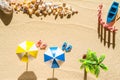 Aerial view of a sandy beach with two umbrellas, pair of flip flops, palm tree, boat, shells. Summer and travel concept.