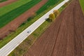 Aerial view of scenic countryside landscape in spring with country road and passenger car on it driving along on sunny spring day Royalty Free Stock Photo