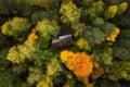 Aerial view of secluded cottage in the woods. Log cabin in the beautiful autumn forest. View from above. Colorful trees.