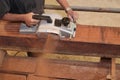 Aerial view of senior carpenter using electric planer on a piece of wood in carpentry workshop. Selective focus and shallow depth