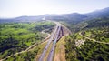 Aerial view shot flying over green hills fields, presents highway road and modern bridge Royalty Free Stock Photo