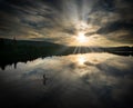 Aerial view of a silhouetted man paddleboarding in a tranquil lake on a cloudy day. Royalty Free Stock Photo