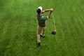 Aerial view of skilled golfer in casual attire, in cap doing completing swing in motion on green turf. Royalty Free Stock Photo