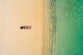 Aerial view of slim woman sunbathing lying on a beach chairin Seychelles. Summer seascape with girl, beautiful waves, colorful