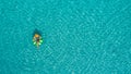 Aerial view of slim woman swimming on the swim ring donut in the transparent turquoise sea in Seychelles. Summer seascape with