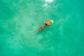 Aerial view of slim woman swimming on the transparent turquoise sea. Summer seascape with girl, beautiful waves, colorful water.