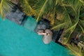 Aerial view of slim young woman in beige bikini and straw hat relaxing near luxury swimming pool and palm trees.Vacation Royalty Free Stock Photo