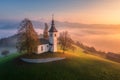 Aerial view of small church on the hill and orange low clouds