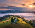 Aerial view of small church on the hill over pink low clouds