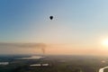 Aerial view of small hot air baloon flying over rural countryside at sunset Royalty Free Stock Photo