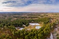 Aerial view of a small lakes inside a forest with conifer trees. Idyllic winter moment with the alp mountains in the Royalty Free Stock Photo