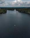 Aerial view of small motorboat on beautiful lake. Boat leaving small waves behind. Finnish lake view. Royalty Free Stock Photo