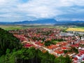 Aerial view of the small Romanian town of Rasnov among green fields and blue Carpathians. Amazing panorama of houses with red Royalty Free Stock Photo