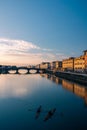 Aerial view of a small rowing boat on a tranquil river during the golden hour of dusk in Florence.