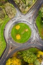 Aerial view of a small traffic roundabout surrounded by colourful trees displaying autumn colours