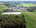 Aerial view of a small village in the distance behind a piece of forest and an asparagus field covered with foil