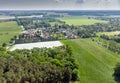 Aerial view of a small village in the distance behind a piece of forest and an asparagus field covered with foil