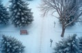 Aerial view of snow covered park with path, trees, and bench. Footprints in snow on pathway. Winter landscape with evergreen Royalty Free Stock Photo