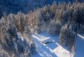 Aerial view of a snowbound hut at a clearing in the winter forest, bavarian alps