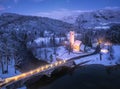 Aerial view of snowy mountains, church, bridge, lights at night Royalty Free Stock Photo