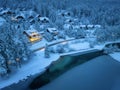 Aerial view of snowy village, road, trees, lake, houses at night Royalty Free Stock Photo