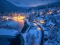 Aerial view of snowy village, trees, lake, street lights at night Royalty Free Stock Photo