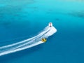 Aerial view of speed boat towing circular floatation device in crystal clear blue water in the ocean