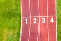 Aerial view of sports stadium with red running tracks with numbers on it and green grass football field Royalty Free Stock Photo