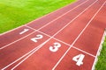 Aerial view of sports stadium with red running tracks with numbers on it and green grass football field Royalty Free Stock Photo