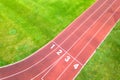 Aerial view of sports stadium with red running tracks with numbers on it and green grass football field Royalty Free Stock Photo