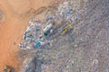 Aerial view of stack of different types of large mountain garbage pile, plastic bags, and trash with a tractor car in industrial Royalty Free Stock Photo