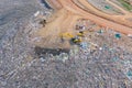Aerial view of stack of different types of large mountain garbage pile, plastic bags, and trash with a tractor car in industrial Royalty Free Stock Photo