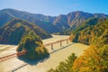 Aerial view of the steam train crossing Oigawa Railroad to go to station with red fall foliage in forest mountain hills and blue Royalty Free Stock Photo