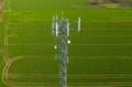 Aerial view on steel telecommunication tower in the middle of green field transmitting radio, telephone and internet signal