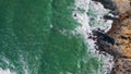 Aerial view stony coastline washing by stormy ocean. Sea waves splashing cliffs.
