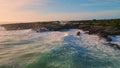 Aerial view stony coastline washing by stormy ocean. Sea waves splashing cliffs