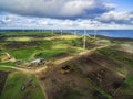Aerial view of stormy clouds above wind turbines and pastures on ocean shore. Royalty Free Stock Photo