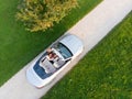 Aerial view of successful man driving and enjoying his silver convertible luxury sports car on the open country side