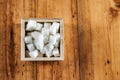 Aerial View of Sugar Cubes in Square Shaped Bowl with Unrefined Sugar spill over in Wooden Background Royalty Free Stock Photo