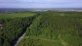 Aerial view of a summer beautiful green forest and a narrow road on blue sky background. Clip. Flying above countryside Royalty Free Stock Photo