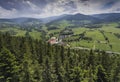 Aerial view of the summer time in mountains near Stronie Slaskie town in Poland. Pine tree forest and clouds over blue sky. View Royalty Free Stock Photo