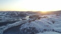 Aerial view: sunrise in the mountains. Snow-covered trees. Village by the river in the mountains. Frosty weather. Winter