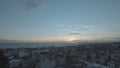 Aerial view of a sunset or a sunrise above the sea and the city. Action. Flying above houses of a coastal town on