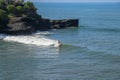 Aerial view of surfer on blue surface of Indian ocean. Riding the waves. Batu Bolong beach on the rocky coast of Bali island,