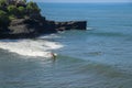 Aerial view of surfer on blue surface of Indian ocean. Riding the waves. Batu Bolong beach on the rocky coast of Bali island,