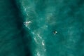 Aerial view of surfers waiting, paddling and enjoying waves in a beautiful blue water Royalty Free Stock Photo
