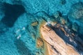 Aerial view of swimming people in blue sea, rocky beach, waves