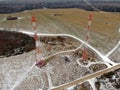 Aerial view telecommunication towers of mobile communication on the background of green field is covered with white snow. Royalty Free Stock Photo