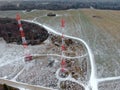 Aerial view telecommunication towers of mobile communication on the background of green field is covered with white snow.